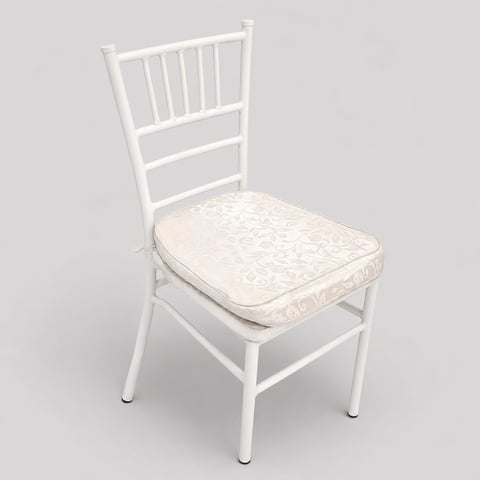 White chiavari chair with cream damask cushion, viewed from front angle on gray background